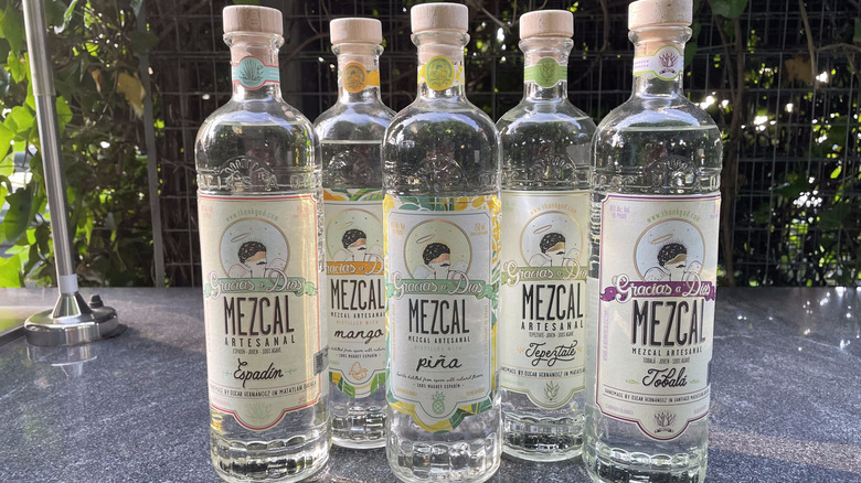 Five bottles of gracias a dios mezcal sit on an outside countertop.