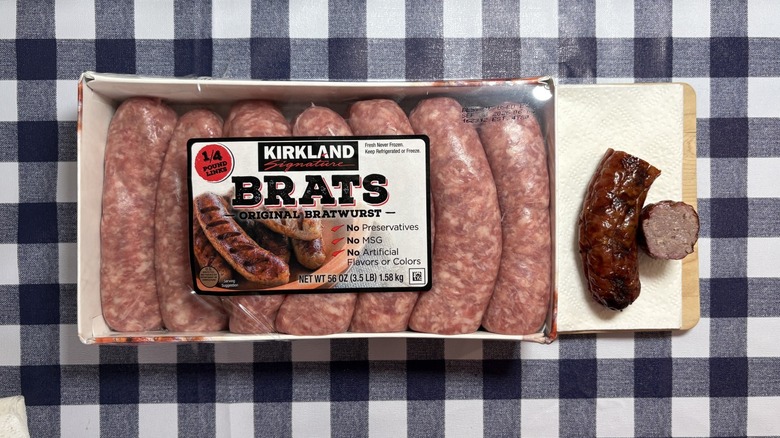 Kirkland brat package next to cooked brat cut in half on checkered tablecloth