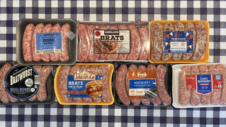 Seven grocery store brat varieties in packages on a blue and white checkered tablecloth