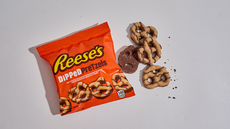 Package of dipped pretzels next to a handful of dipped pretzels on a table