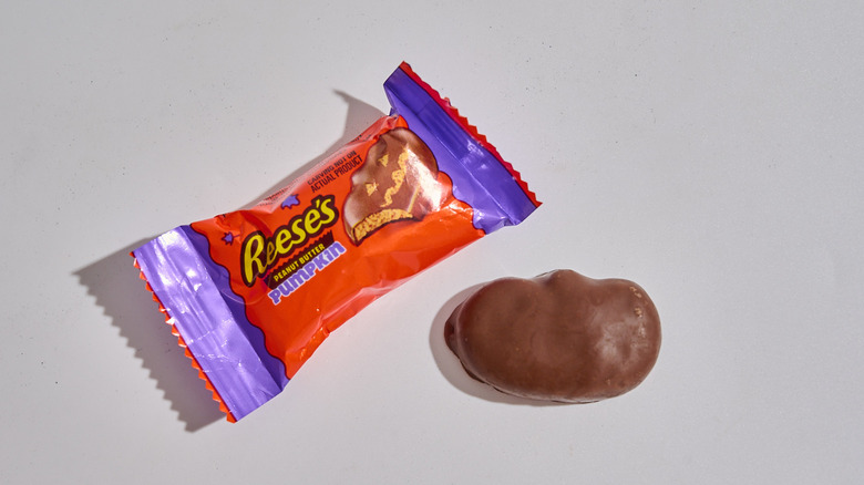 A wrapped Reese's Peanut Butter Pumpkin next to an unwrapped one on a table