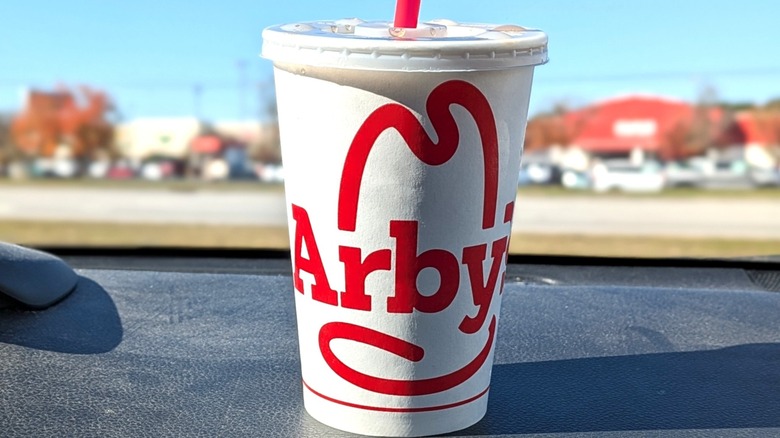 Arby's soda sitting on a dashboard