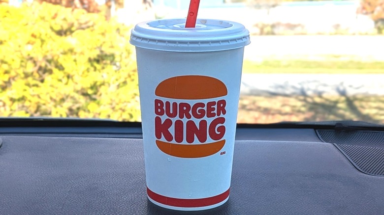 A Burger King cup of Diet Coke on a dashboard