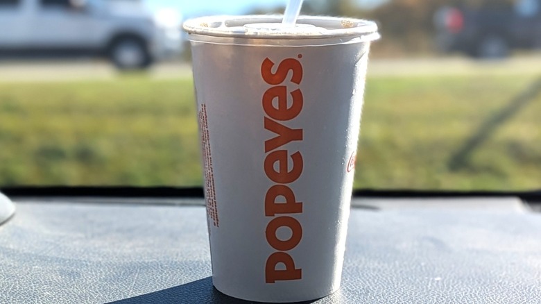 A Popeyes cup of Diet Coke on a dashboard