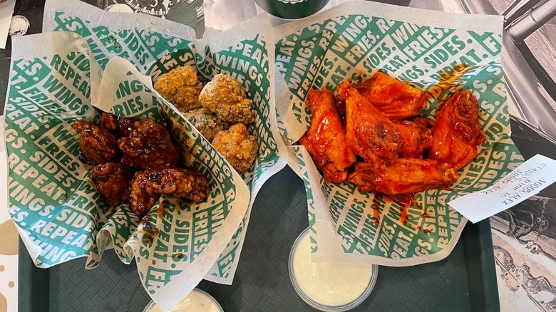 Three different styles of chicken wings wrapped in takeout paper