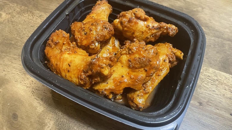 Little Caesar Wings in a black takeout container.