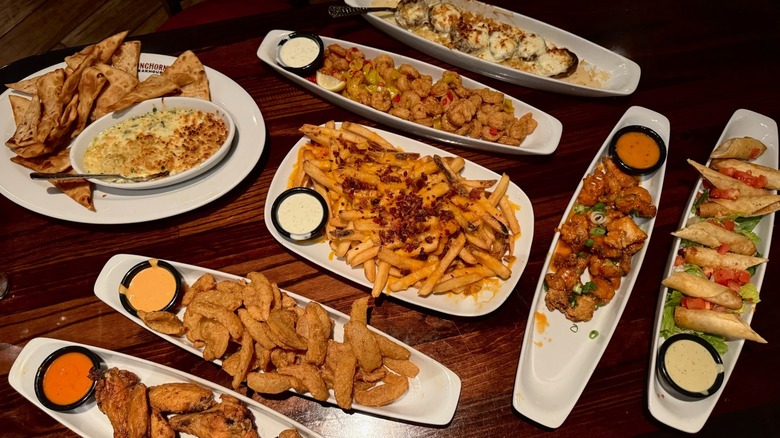 Top-down view of various appetizers on wooden table.