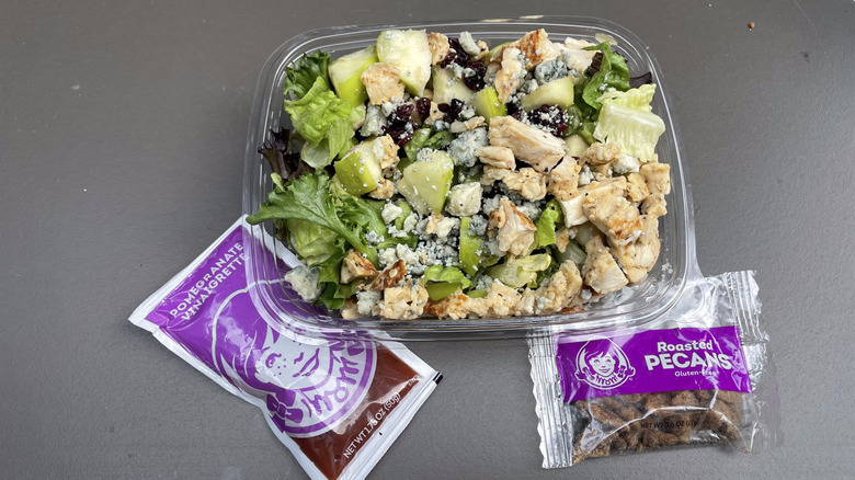 A Wendy's apple pecan salad with chunks of blue cheese and apples sits on a table.