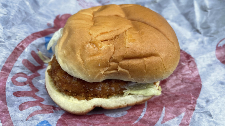 A chicken patty on a bun sits on a Wendy's wrapper.