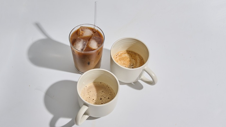 iced coffee and two cups of hot coffee on a table
