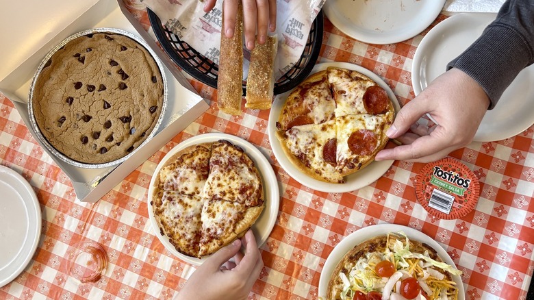 A view from above of Pizza hut pizzas, breadsticks, and a large chocolate chip cookie