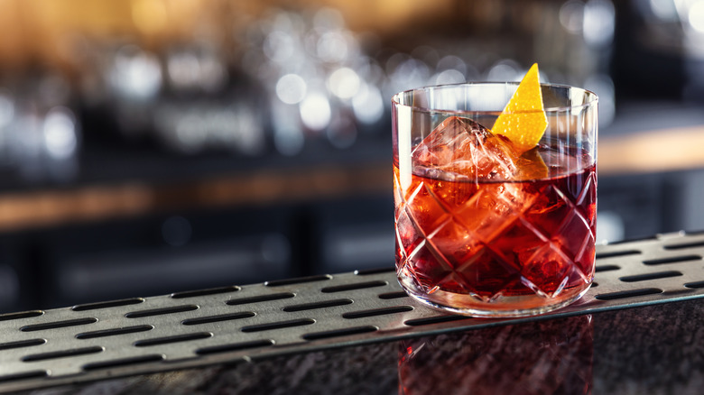Negroni with single ice cube sitting on bar