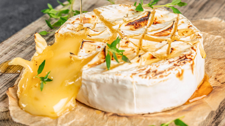 Split-open baked brie topped with honey and herbs