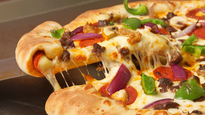 A slice of stuffed-crust supreme pizza is removed from a pie