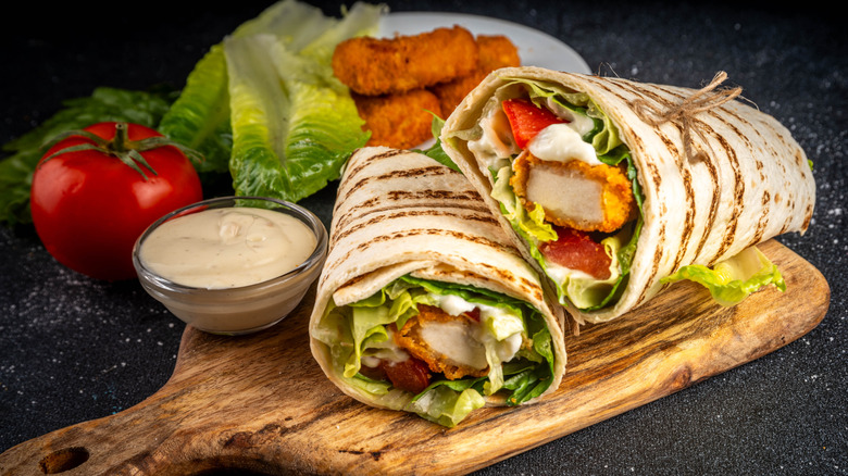A crispy chicken wrap with lettuce, tomatoes, and dressing