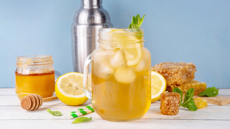 A cocktail made with honey and lemon served over ice in a Mason jar