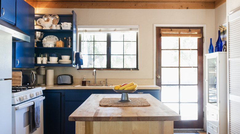 A cozy kitchen with bright windows and a central island topped with a display of fresh fruits