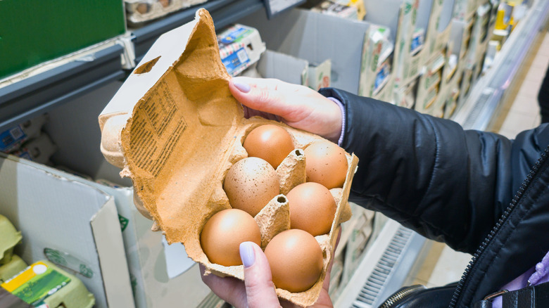 Person holding an open half carton of eggs in store