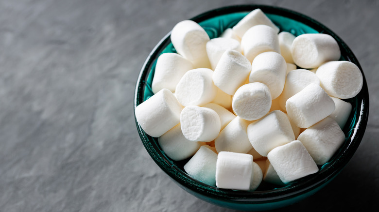 Green and black bowl filled with marshmallows on a gray table