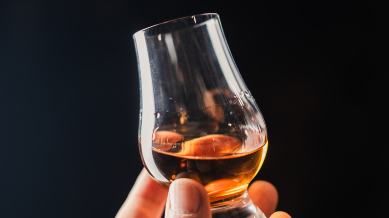 Hand holding a glass of whisky