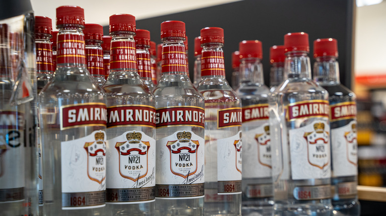 Numerous Smirnoff vodka bottles on a store shelf.