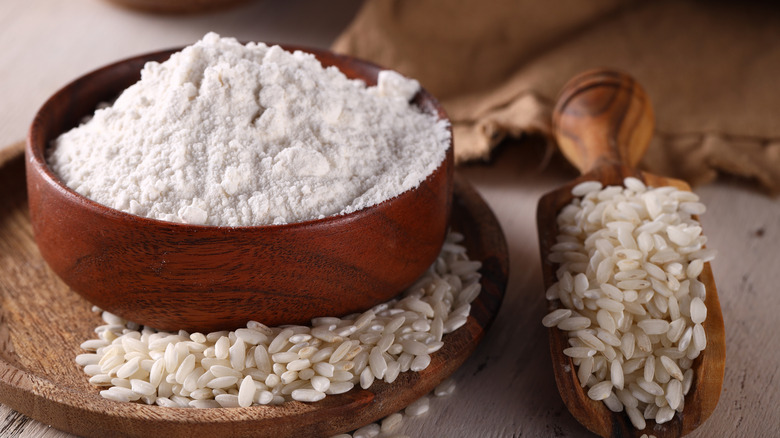 Rice flour in a wooden bowl with rice grains on the side