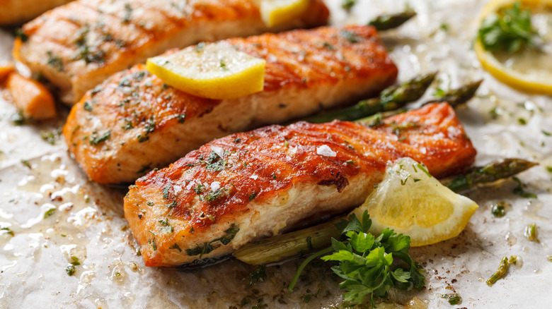 Baked salmon with lemon wedges and herbs.