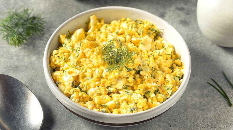 Egg salad with fresh dill in a shallow cream-colored bowl
