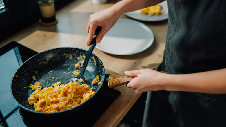 Person cooking scrambled eggs at home
