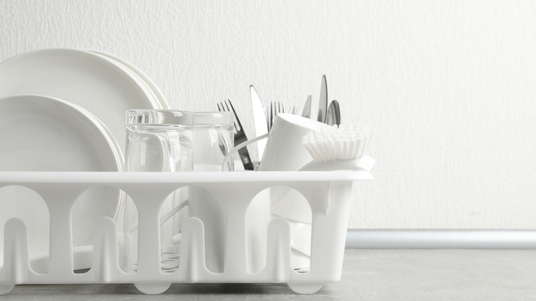 White dish drainer on a countertop in front of a white wall.