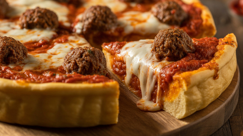 Thick crust meatball pizza on a cutting board.