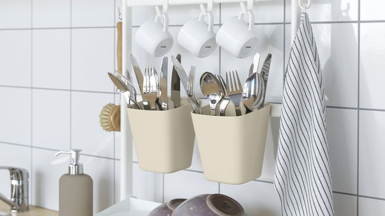 Sunnersta storage containers filled with silverware, plus cups and towels hanging near it in a kitchen