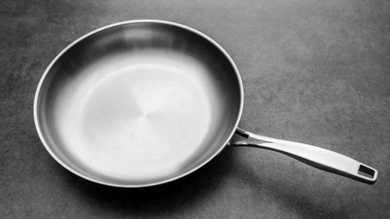 Stainless steel pan on stone surface.