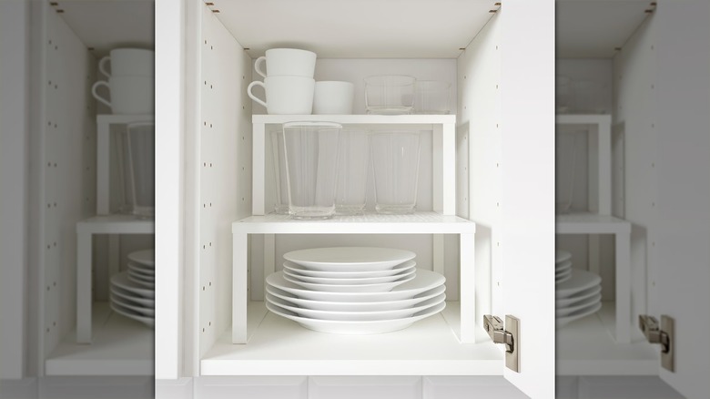 two ikea variera shelf inserts stacked on top of each other inside a dish cabinet