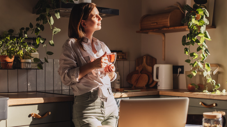 A person wears a satisfied expression in a cozy kitchen.