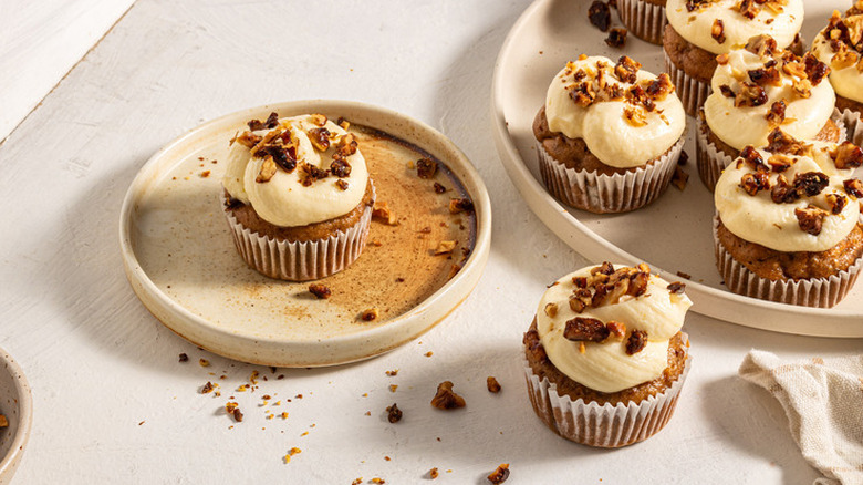 A platter of carrot cake cupcakes topped with caramelized walnuts.