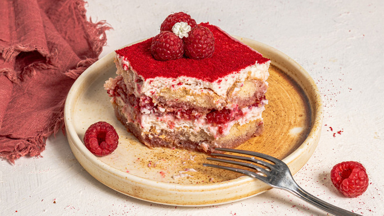 A slice of raspberry and cream tiramisu on a plate with a fork.