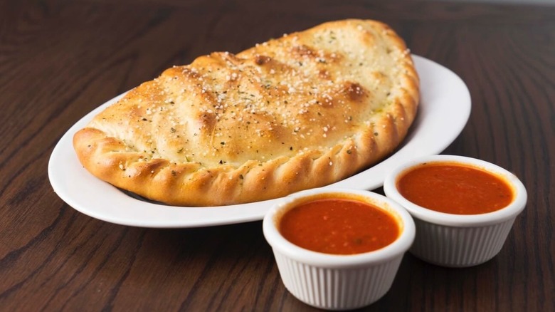A calzone on a plate with marinara sauce at Rosati's Pizza