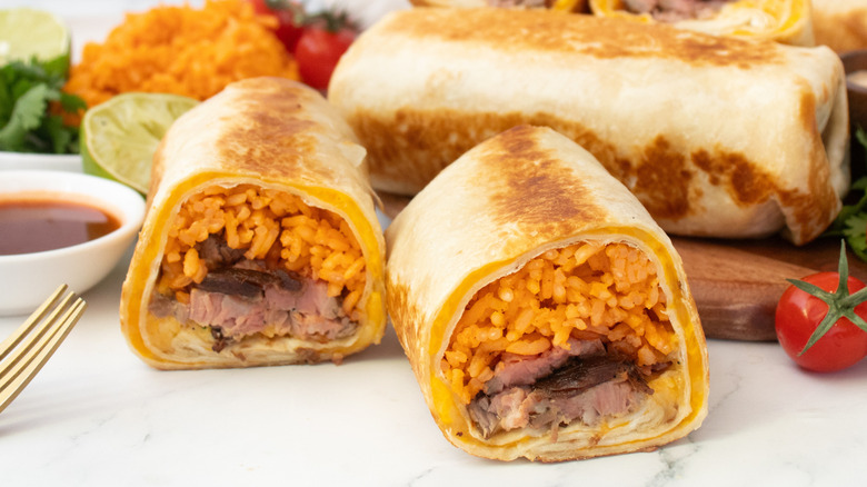 Side shot of a halved Quesaritos with seasoned rice on the side.