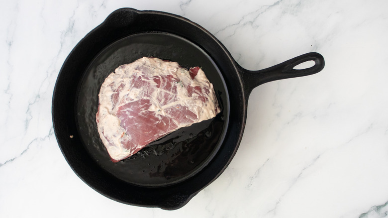 Marinated steak in a large cast iron skillet