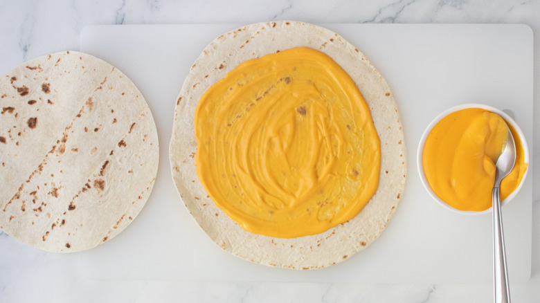 A large flour tortilla spread with nacho cheese sauce