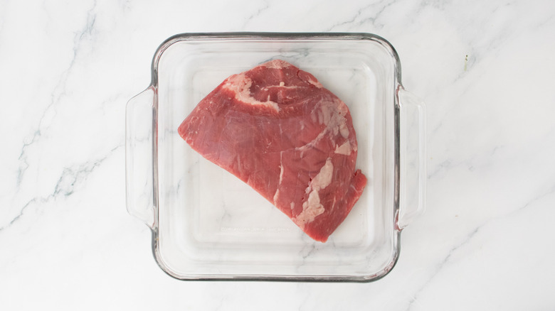 A portion of skirt steak in a square casserole dish