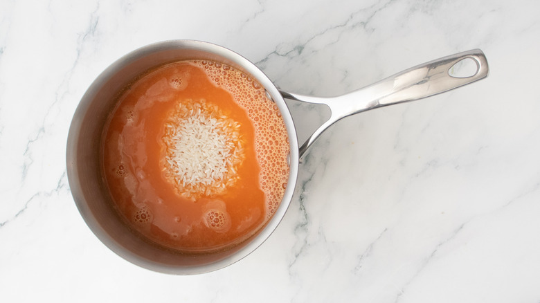 A medium saucepan with rice and a red broth