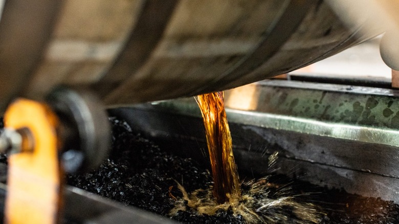 Whiskey being poured out of a barrel to be blended