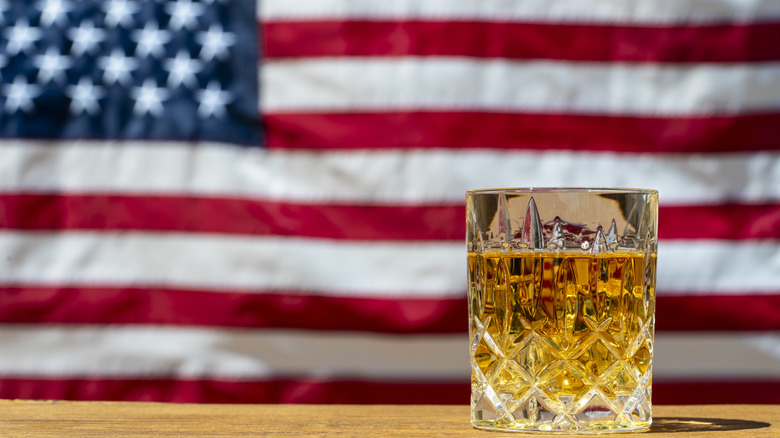 Glass of whiskey in front of an American flag