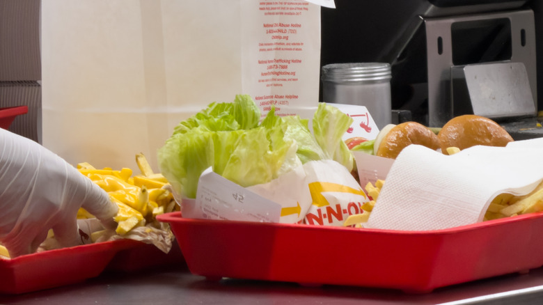 Fast food kitchen workers working with Trays of burgers and fries ready to be picked up by the customers at a local In n Out burger restaurant