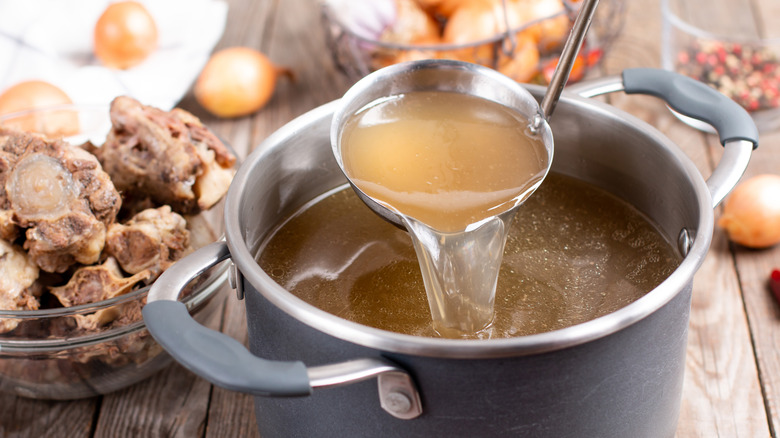 A pot of chicken stock on a rustic wooden table.