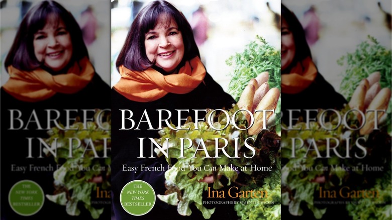 Book cover for Barefoot in Paris, showing Ina Garten, wearing a black shirt and orange scarf, holding a selection of leafy greens and baguettes