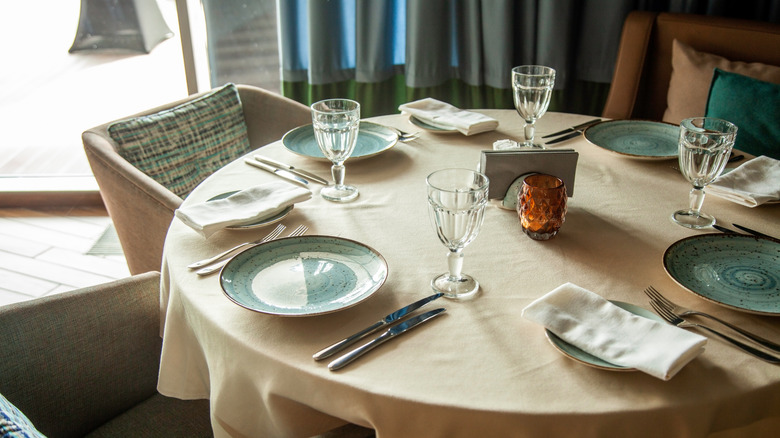 Table set for four people with tan tablecloth and seafoam green plates