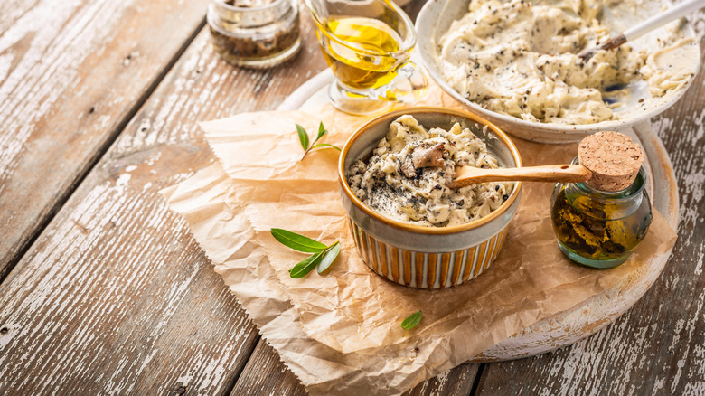 A small bowl of truffle butter on a rustic wooden table.